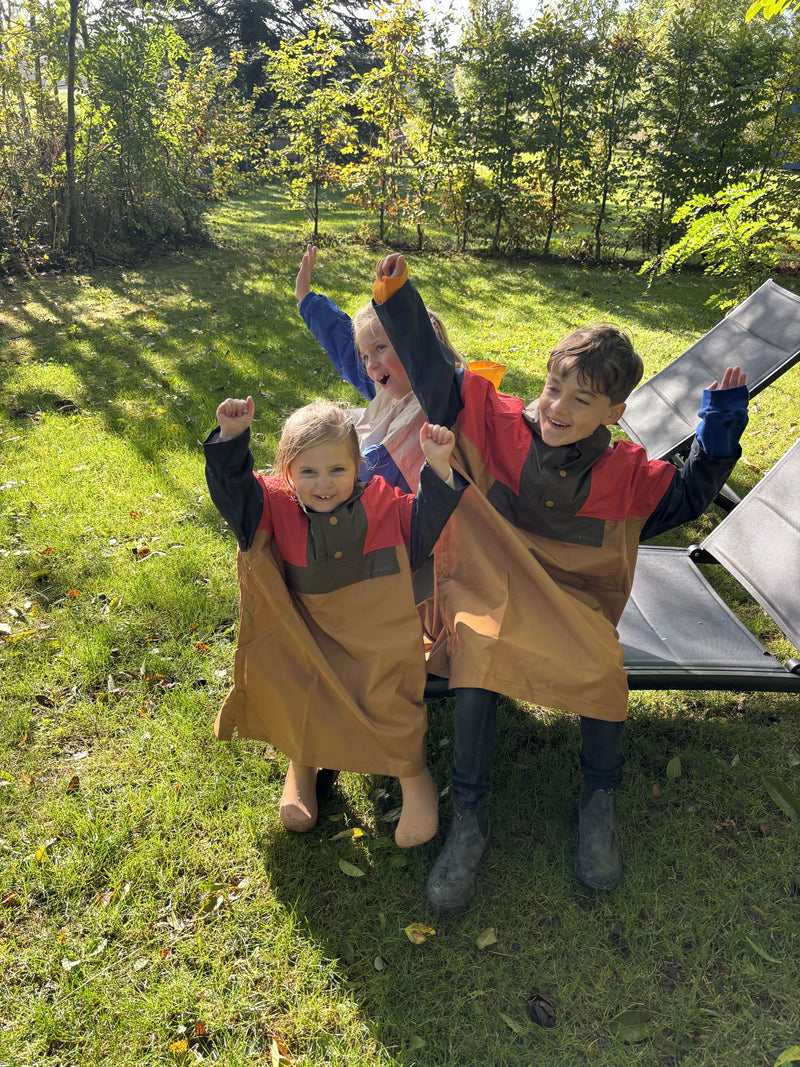 Enfants souriant avec Blundstone, botte de pluie Bisgaard et poncho Liewood